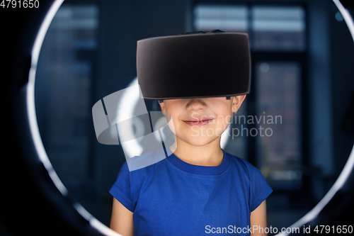 Image of boy in vr glasses over illumination in dark room