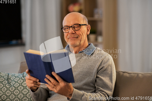 Image of happy bald senior man on sofa reading book at home