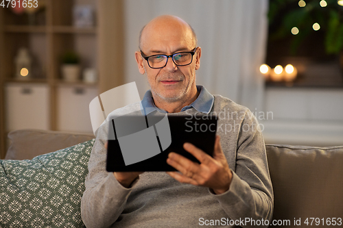 Image of happy senior man with tablet computer at home