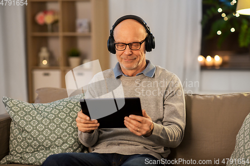 Image of senior man with tablet pc and headphones at home