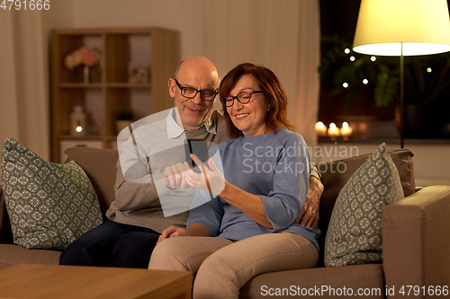 Image of happy senior couple with smartphone at home