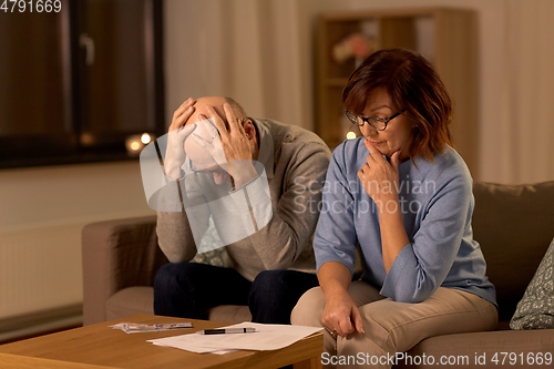 Image of unhappy senior couple with bills and money at home