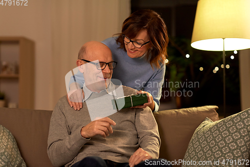 Image of happy senior couple with gift box at home