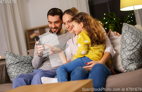 Image of happy family with smartphone at home at night