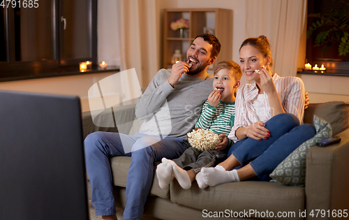 Image of happy family with popcorn watching tv at home