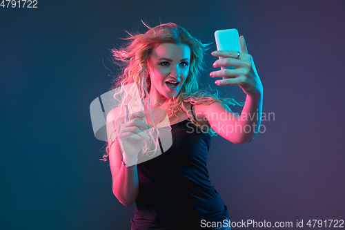 Image of Caucasian young woman\'s portrait on gradient background in neon light