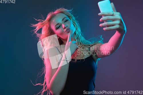 Image of Caucasian young woman\'s portrait on gradient background in neon light