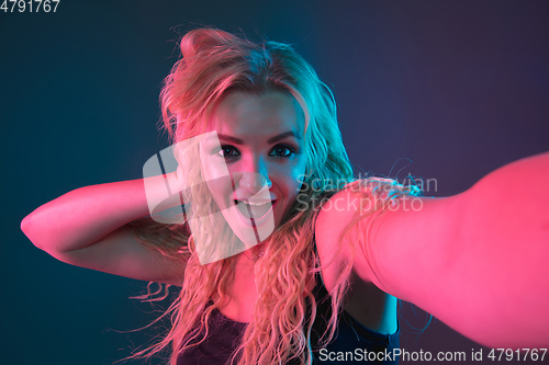 Image of Caucasian young woman\'s portrait on gradient background in neon light