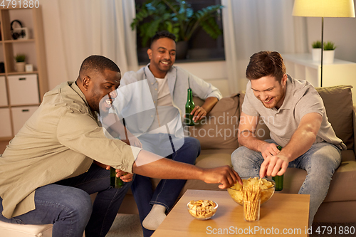 Image of male friends drinking beer with crisps at home