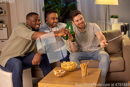 Image of male friends with smartphone taking selfie at home
