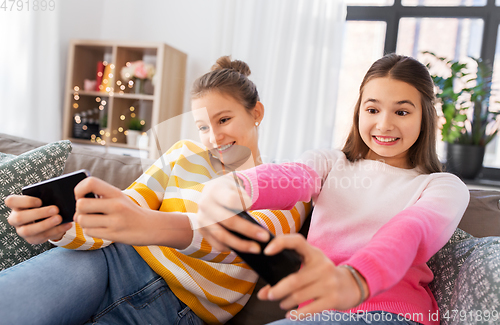 Image of girls and playing game on smartphones at home