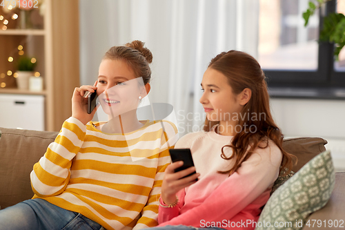 Image of happy teenage girls with smartphones at home