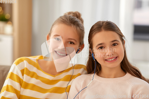 Image of happy girls with earphones listen to music at home