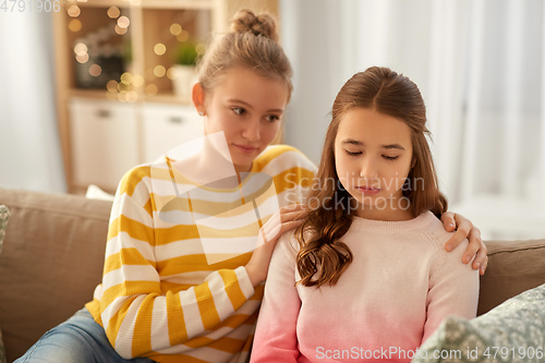 Image of teenage girl comforting her sad friend at home