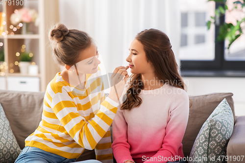 Image of happy teenage girls doing make up at home