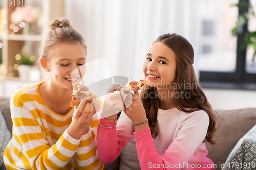 Image of happy teenage girls eating pizza at home