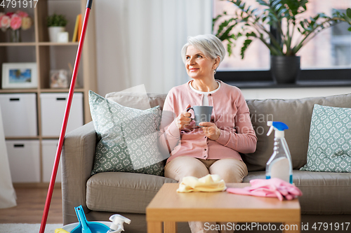 Image of senior woman drinking coffee after home cleaning