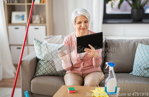 Image of old woman with tablet pc and credit card at home