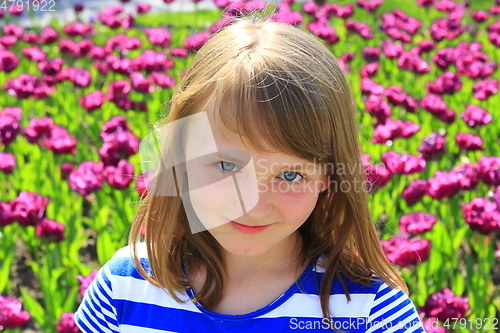 Image of portrait of little girl stand by lilac tulips