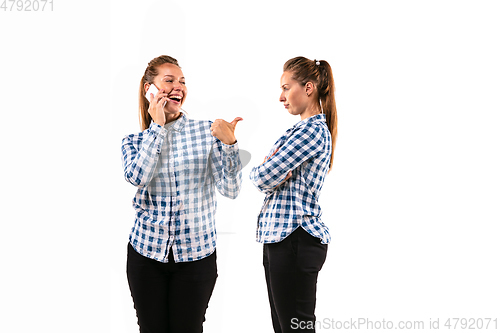 Image of Young handsome woman arguing with herself on white studio background.