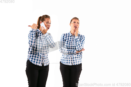 Image of Young handsome woman arguing with herself on white studio background.