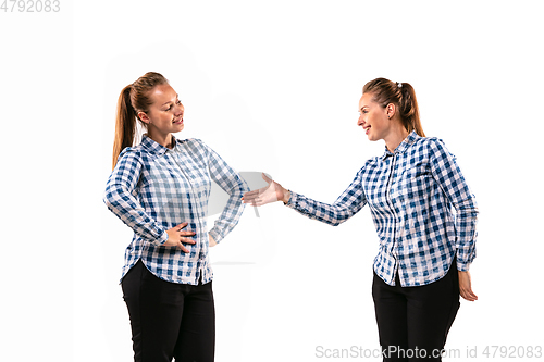 Image of Young handsome woman arguing with herself on white studio background.