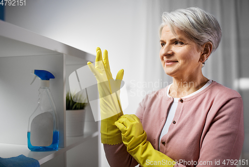 Image of senior woman putting protective rubber gloves on