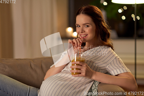 Image of happy pregnant woman drinking juice at home