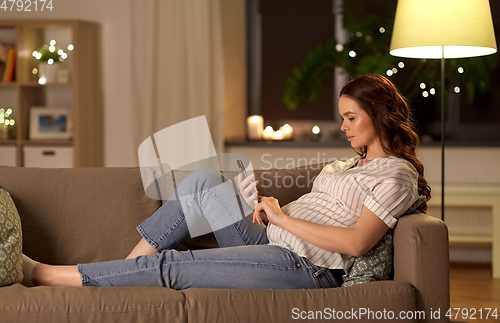 Image of happy pregnant woman with smartphone at home