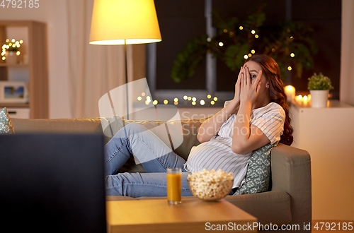 Image of scared pregnant woman watching tv at home