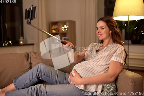 Image of happy smiling pregnant woman taking selfie at home