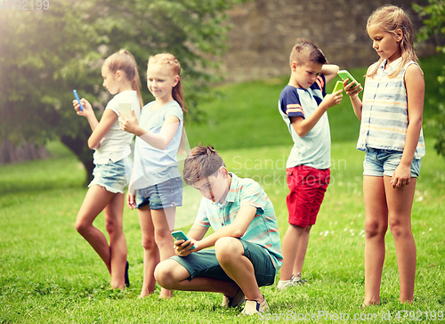 Image of kids with smartphones playing game in summer park