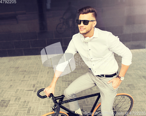 Image of man with bicycle and headphones on city street