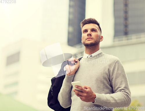 Image of young man with smartphone and bag in city