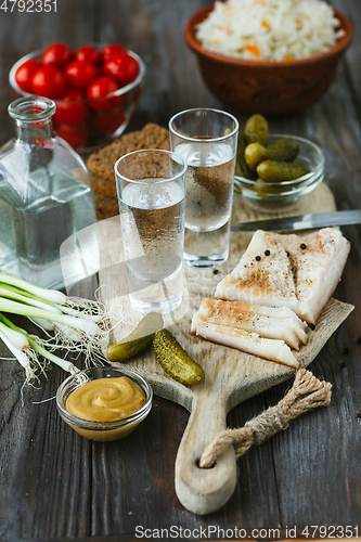 Image of Vodka and traditional snack on wooden background