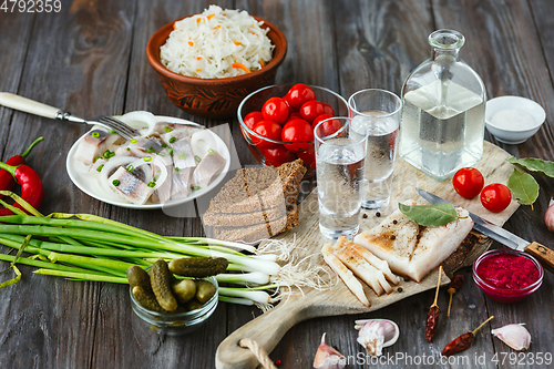 Image of Vodka and traditional snack on wooden background