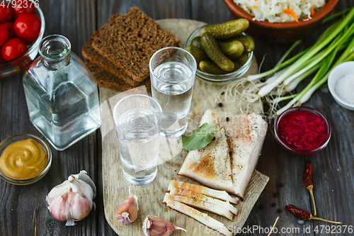 Image of Vodka and traditional snack on wooden background