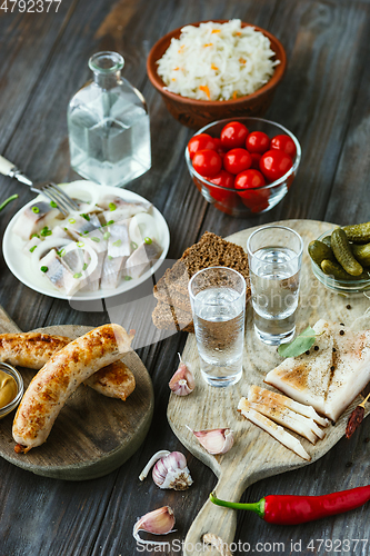 Image of Vodka and traditional snack on wooden background