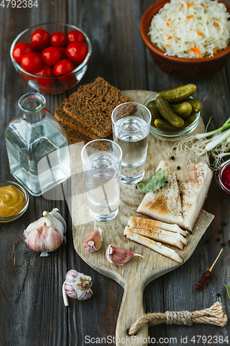 Image of Vodka and traditional snack on wooden background