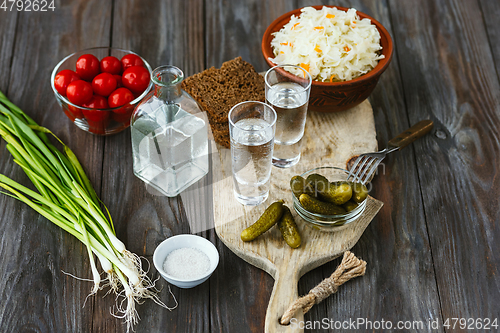 Image of Vodka and traditional snack on wooden background