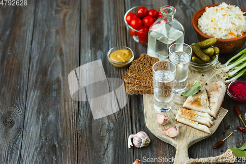 Image of Vodka and traditional snack on wooden background