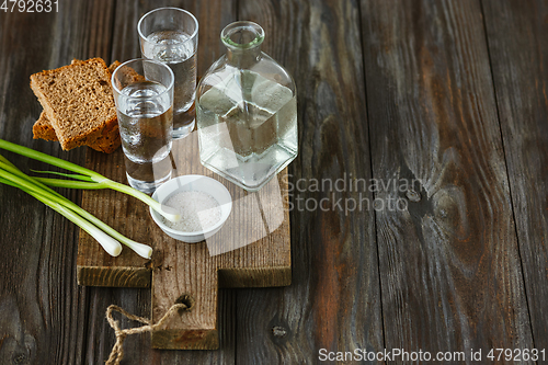 Image of Vodka and traditional snack on wooden background