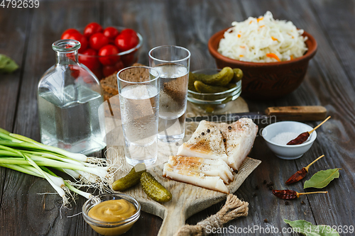 Image of Vodka and traditional snack on wooden background