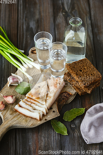 Image of Vodka and traditional snack on wooden background