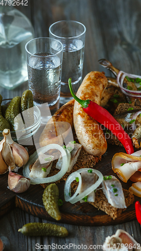 Image of Vodka and traditional snack on wooden background