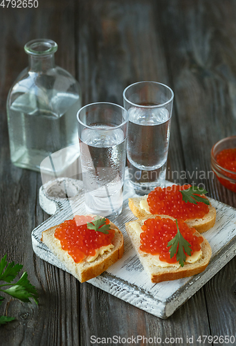 Image of Vodka and traditional snack on wooden background