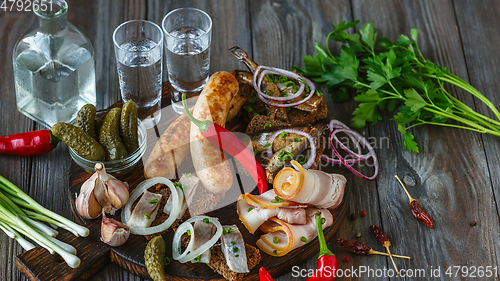 Image of Vodka and traditional snack on wooden background