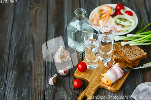 Image of Vodka and traditional snack on wooden background