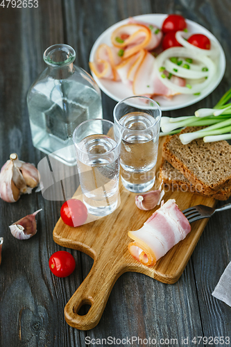 Image of Vodka and traditional snack on wooden background