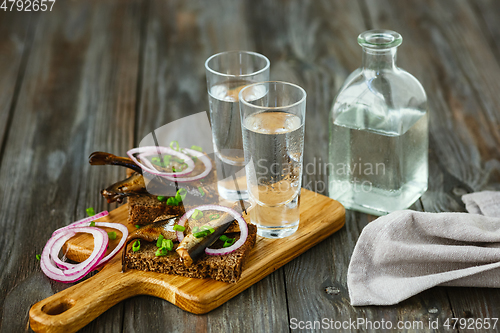 Image of Vodka and traditional snack on wooden background